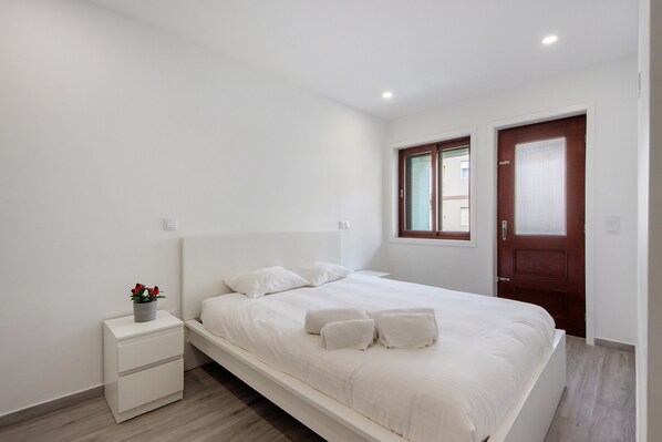 Une chambre à coucher avec un lit, une table de chevet, une fenêtre et une porte.