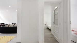 A modern hotel room with a bed, a nightstand, a sofa, and a wardrobe.