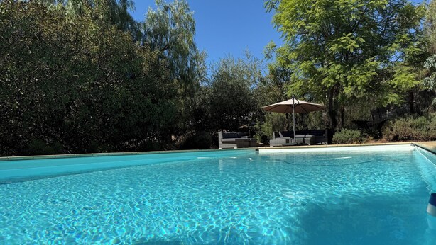 A clear swimming pool with a lounge area in the background.