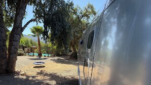 A campsite with a gravel ground, trees, and a swimming pool.