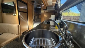 A compact kitchen with a stainless steel sink, a built-in microwave, and a small refrigerator.