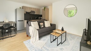A modern living room with a grey sofa, a coffee table, and a dining area with chairs and a small table.