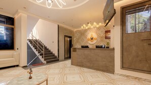 Eine moderne Hotelhalle mit Treppe, Empfangstresen und einem gemusterten Boden.