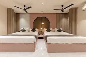 Une chambre d’hôtel avec deux lits, des ventilateurs de plafond, un luminaire central et une grande fenêtre en arc de cercle.