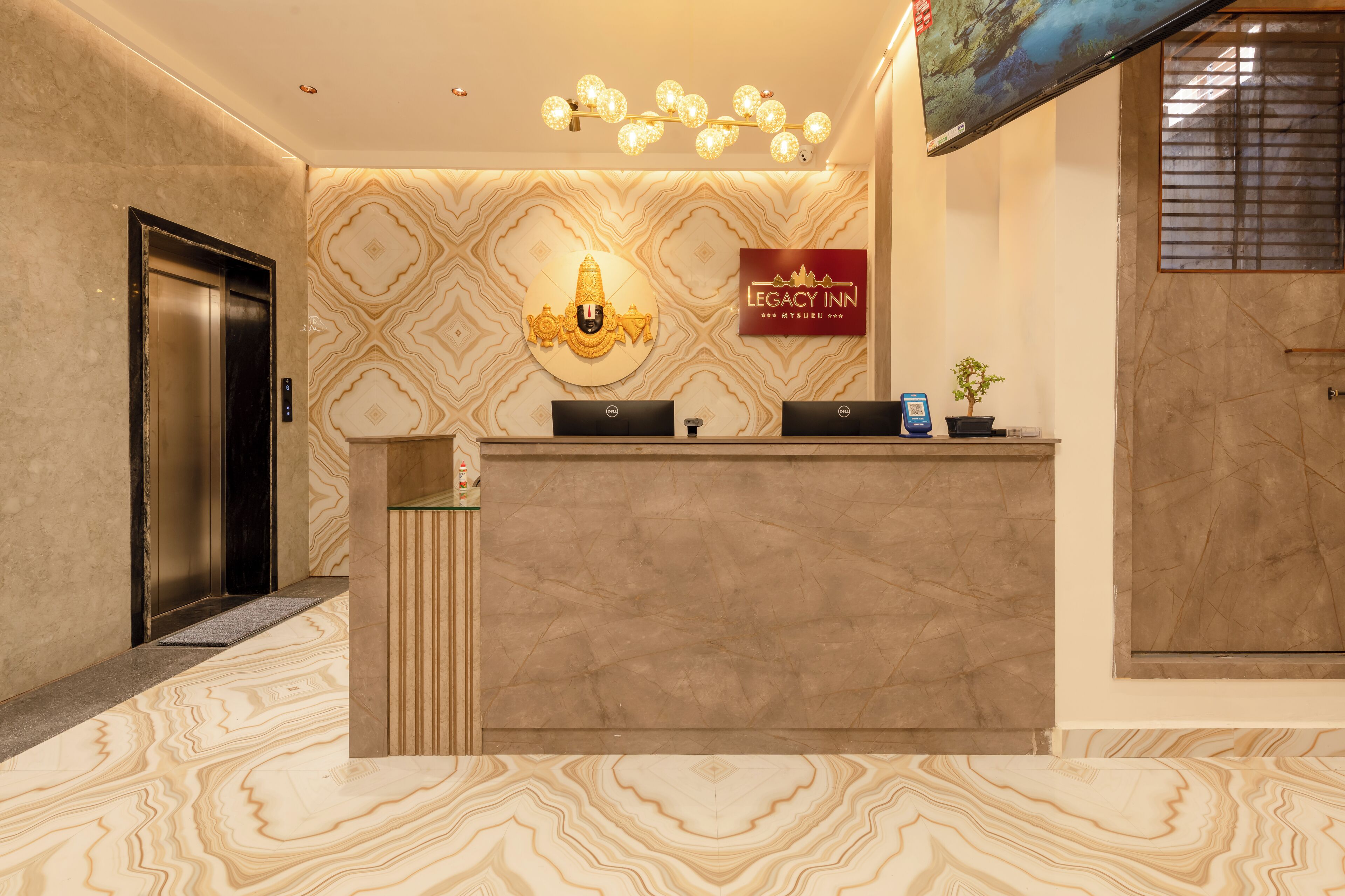 A reception desk with a marble floor, a wall-mounted sign for Legacy Inn, and an elevator to the left.