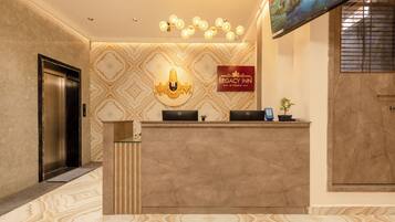 A reception desk with a marble floor, a wall-mounted sign for Legacy Inn, and an elevator to the left.