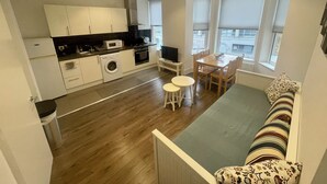 Eine kompakte Wohnung mit Küchenzeile, Essbereich und Sofa.