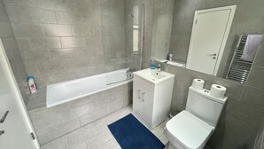 Ein modernes Badezimmer mit Badewanne, Waschbecken, Toilette und Spiegel.