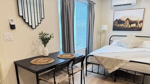 A neatly arranged bedroom with a bed, bedside table, and a small table with chairs. - The Sable Stay (Vancouver)