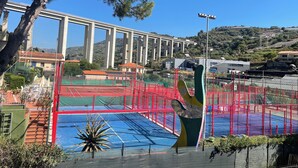 Une vue d’un terrain de sport avec une grande sculpture, un pont et des bâtiments en arrière-plan.
