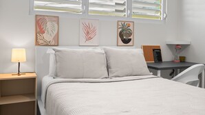 A neatly arranged bedroom with a bed, bedside table, lamp, and artwork on the wall. - Modern 2 BR Apt Great Location Smart TV AC (Manati)