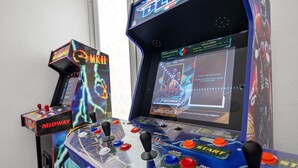 En spillehal med flere joysticks og en skærm, der viser spilindstillinger.