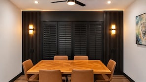 A conference room with a rectangular table, six chairs, black acoustic panels, two wall-mounted lights, and a ceiling fan. - Spacious Golf Course Home with Pool Sleep 12 (Rotonda West)