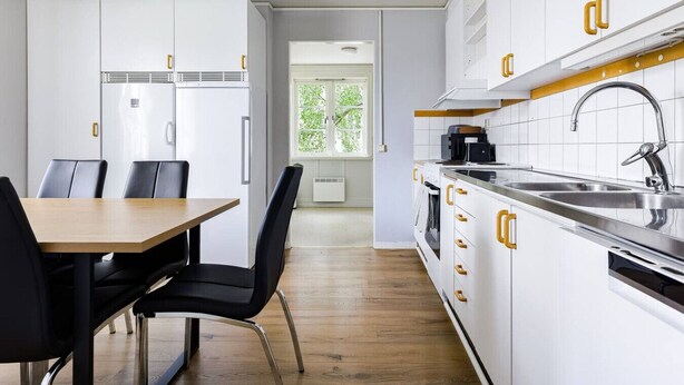 A modern kitchen with white cabinets, a wooden dining table, and black chairs. - Bright & Spacious Getaway (Marmaverken)