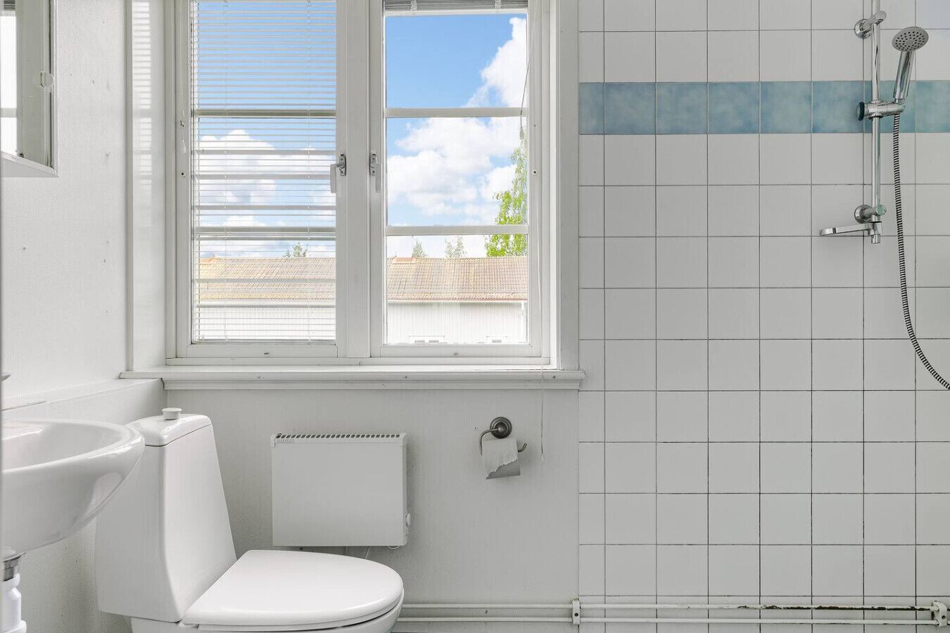 A bathroom with a toilet, a window, and a shower.