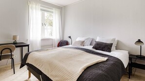A bedroom with a bed, bedside tables, a desk, and a chair. - Bright & Spacious Getaway (Marmaverken)