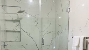 A modern bathroom with a glass-enclosed shower, a toilet, and a towel rack. - Welcome to The Studio Nest — your peaceful perch in paradise. (Diego Martin)