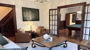 Un salon spacieux avec une table basse en bois, un canapé, un fauteuil et une table de billard.