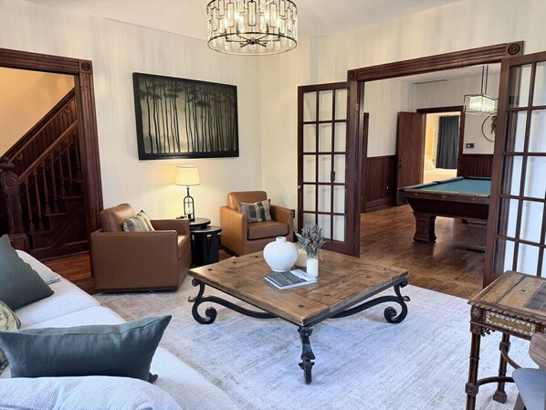 Un salon spacieux avec une table basse en bois, un canapé, un fauteuil et une table de billard.