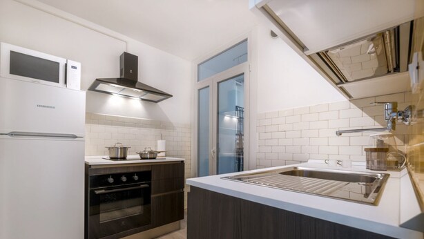 Een moderne keuken met een inbouwoven, magnetron en een spoelbak van roestvrij staal.