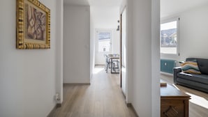 Een gang die leidt naar een eetgedeelte met een tafel, stoelen, een bank en een radiator.