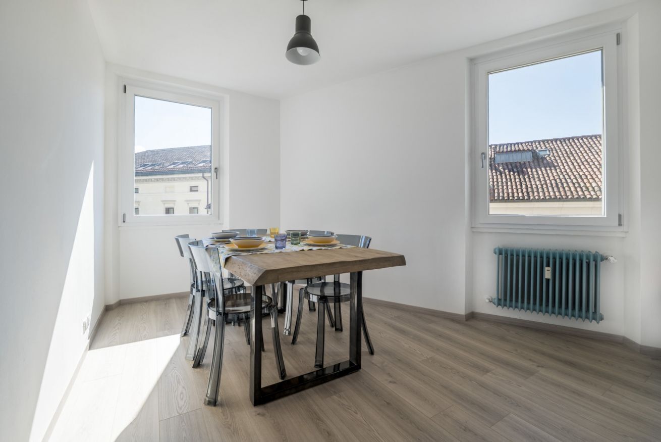 A dining area with a table, chairs, and a hanging light fixture.