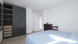 Een slaapkamer met een bed, een kledingkast en een bureau.