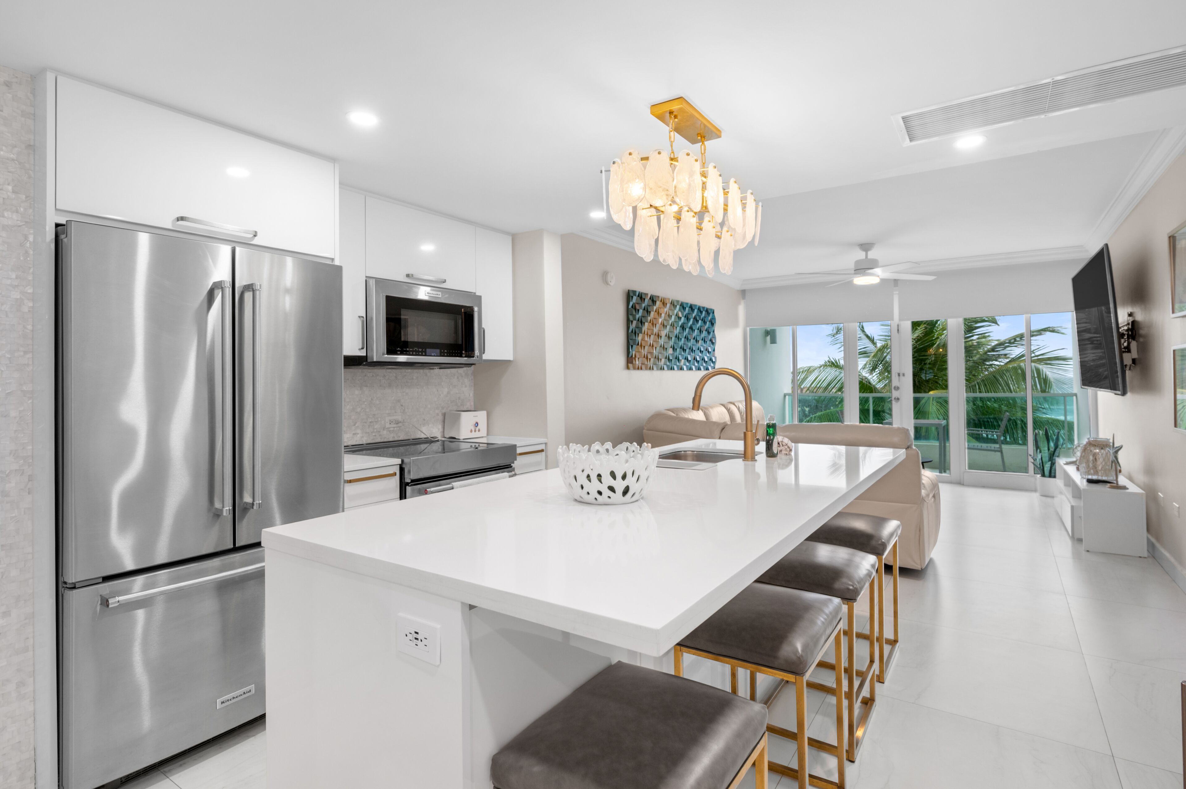 A modern kitchen with a stainless steel refrigerator, a microwave, and a large island with bar stools.