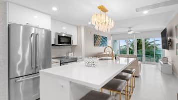 A modern kitchen with a stainless steel refrigerator, a microwave, and a large island with bar stools.