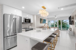 Una cocina moderna con un refrigerador de acero inoxidable, un microondas y una isla grande con taburetes de bar.