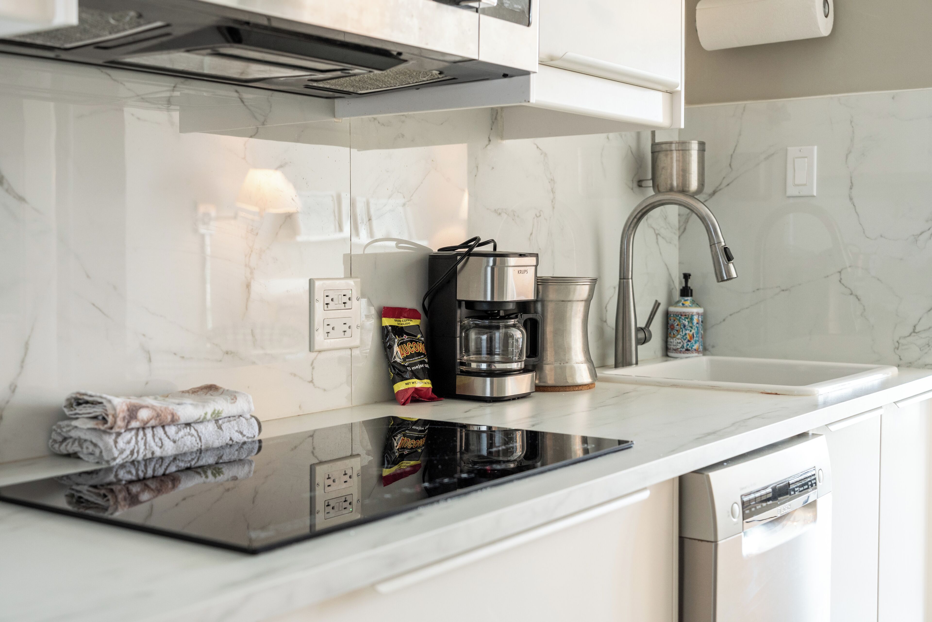 Eine moderne Küche mit Einbauherd, Kaffeemaschine und Geschirrspüler.