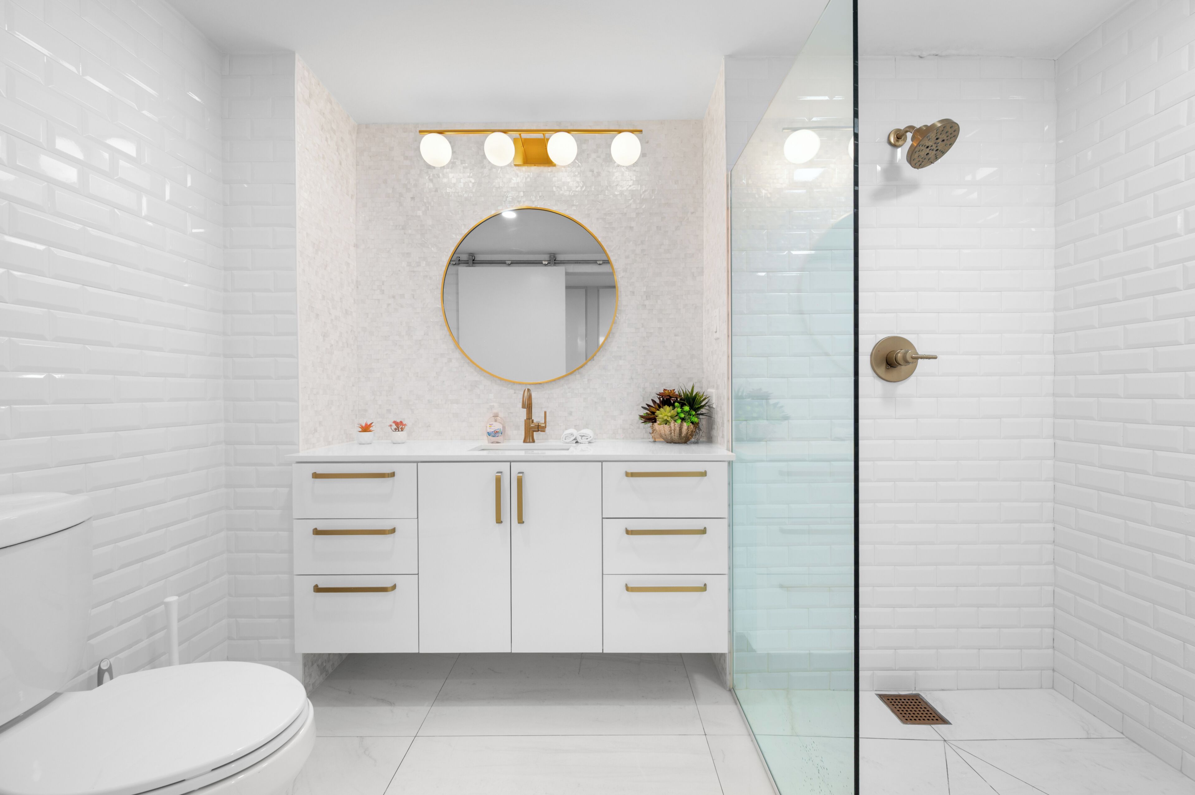 A modern bathroom with a toilet, a sink with a mirror, and a shower area.