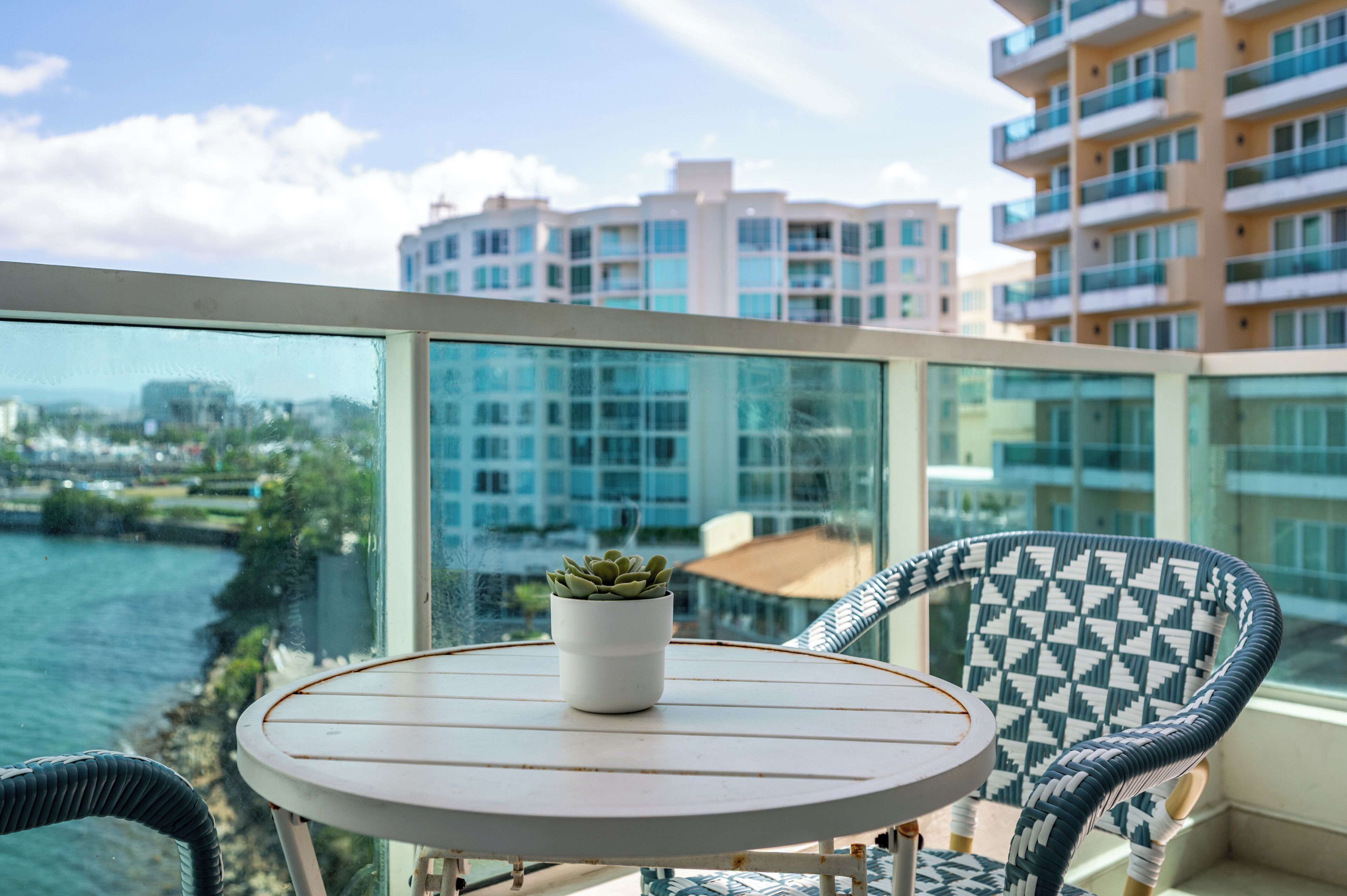 Un balcon avec une table, des chaises et un pot de fleurs.