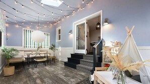 Una camera accogliente con pavimento in legno, un'area pranzo con tavolo e sedie, un divano e una finestra con tende a righe. Si vede una scala che conduce a un altro livello.