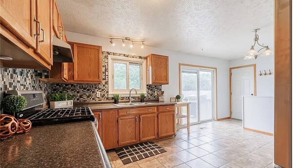 A modern kitchen with wooden cabinets, a granite countertop, and a tiled backsplash. - Charming 2-bedroom + office house, safe, quiet, and convenient (Rochester)