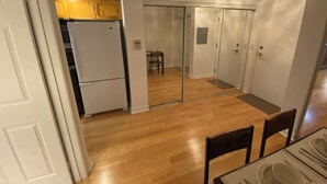 Eine kleine Küche mit Kühlschrank, Holzschränken und einer Essecke mit Tisch für zwei Personen.