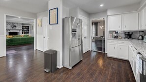 Une cuisine moderne avec des meubles blancs, des appareils en acier inoxydable et un plancher en bois.