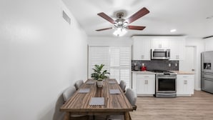 Una cocina moderna con armarios blancos, microondas y refrigerador de acero inoxidable.