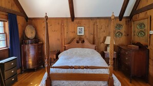 Ein traditionelles hölzernes Betttuch mit Muster, zwei Nachttische aus Holz, eine Kommode und ein Spiegel mit dekorativen Tellern.