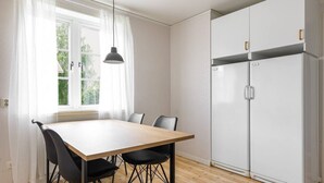 Un coin repas avec une table et des chaises, une fenêtre avec des rideaux et une armoire blanche.