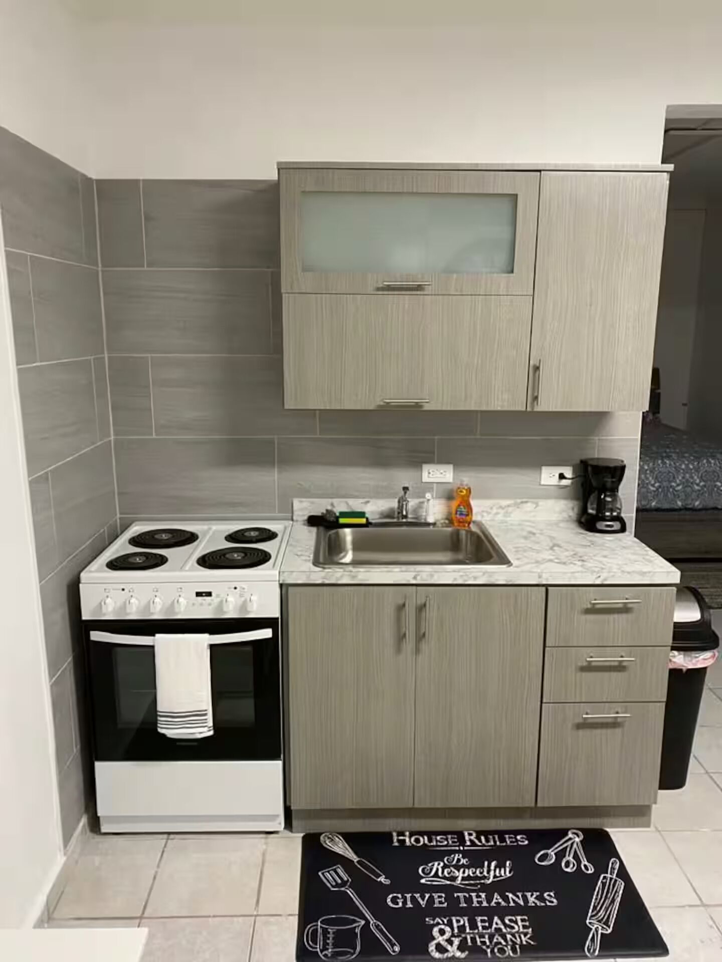 A compact kitchen with a stove, oven, sink, and cabinets.