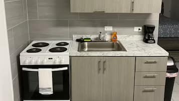 A compact kitchen with a stove, oven, sink, and cabinets.