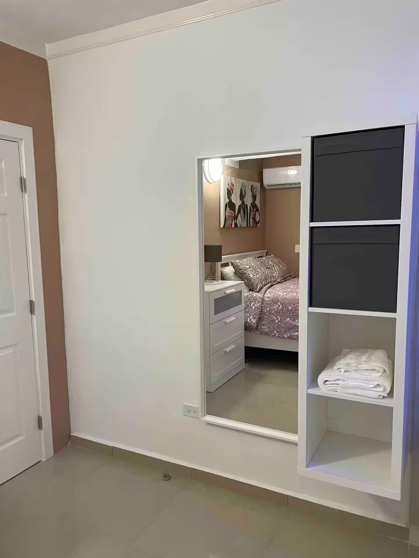 Un dormitorio con cama, mesita de noche, armario y espejo.