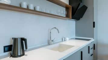 A modern kitchen with a white countertop, stainless steel sink, and a black hanging appliance.