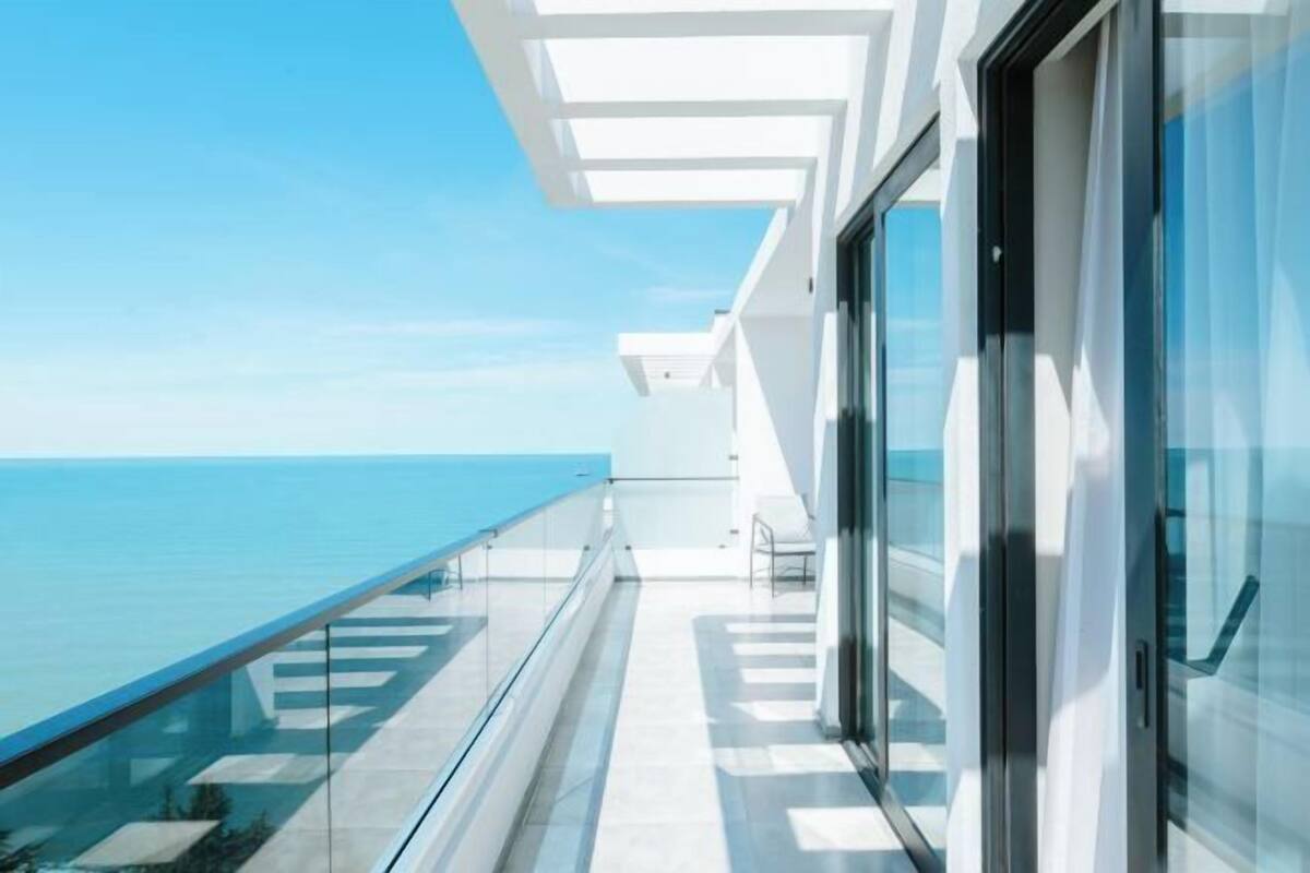 Un bâtiment moderne doté d’un balcon en verre donnant sur la mer.