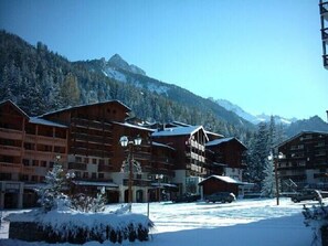 A snow-covered mountain resort with wooden buildings and a clear view of the mountains. - 50m from ski slopes, 1st floor, balcony, tv, ski locker, 23m², Valfréjus (Valfréjus)