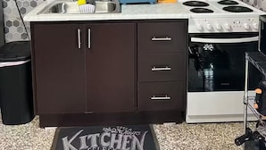A compact kitchen with dark cabinets, a white stove, and a sink.