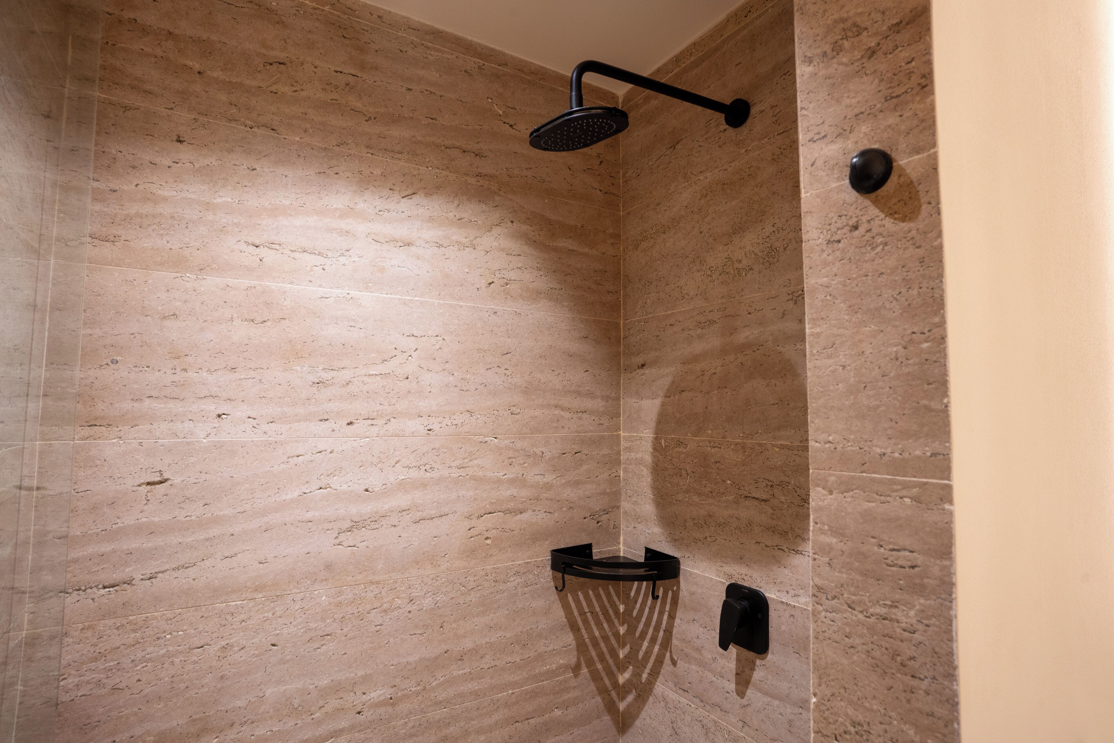 Ein Badezimmer mit Dusche, Handtuchhalter und einer Wandleuchte.