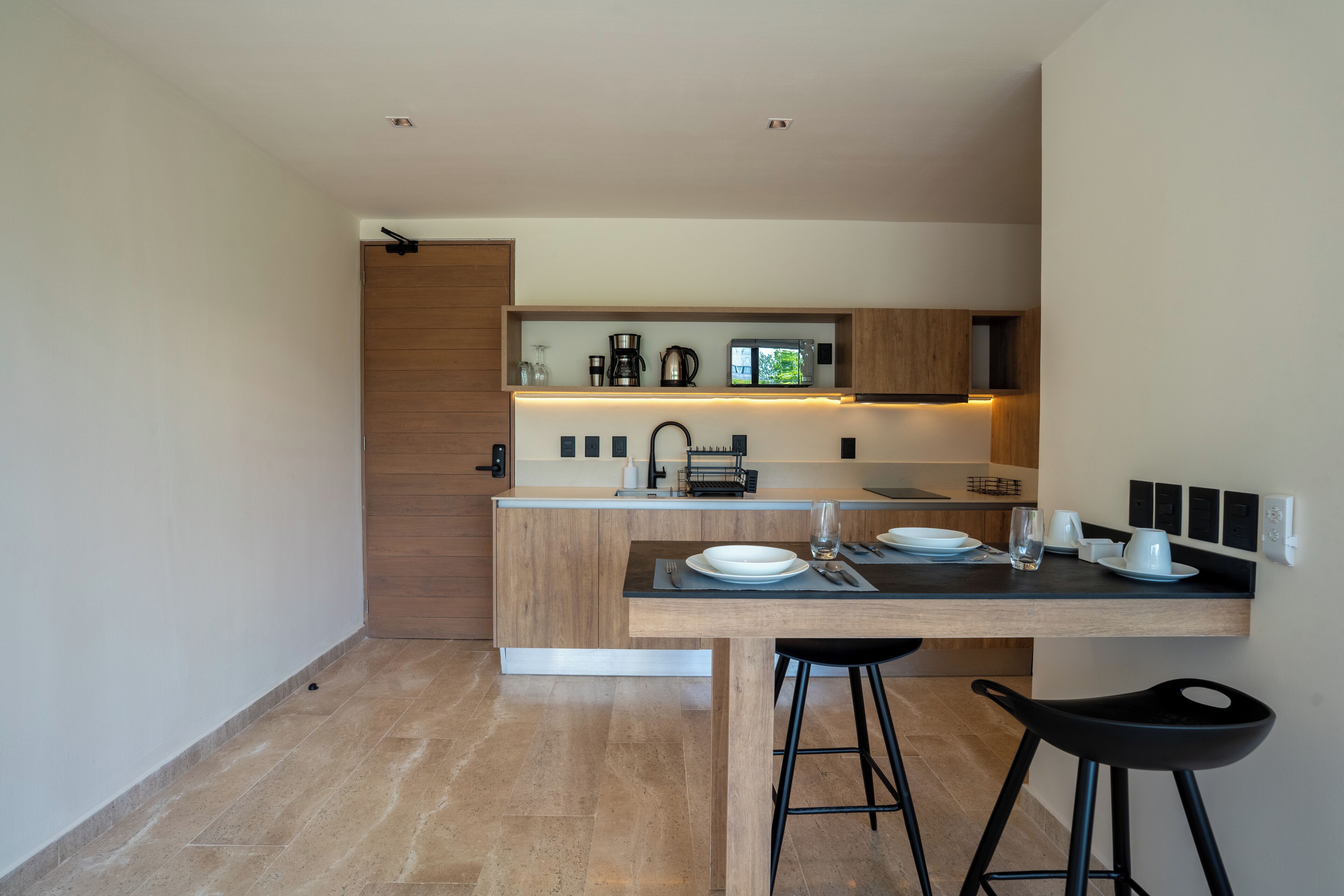 Una cocina moderna con encimera de madera, un lavabo y taburetes de bar.