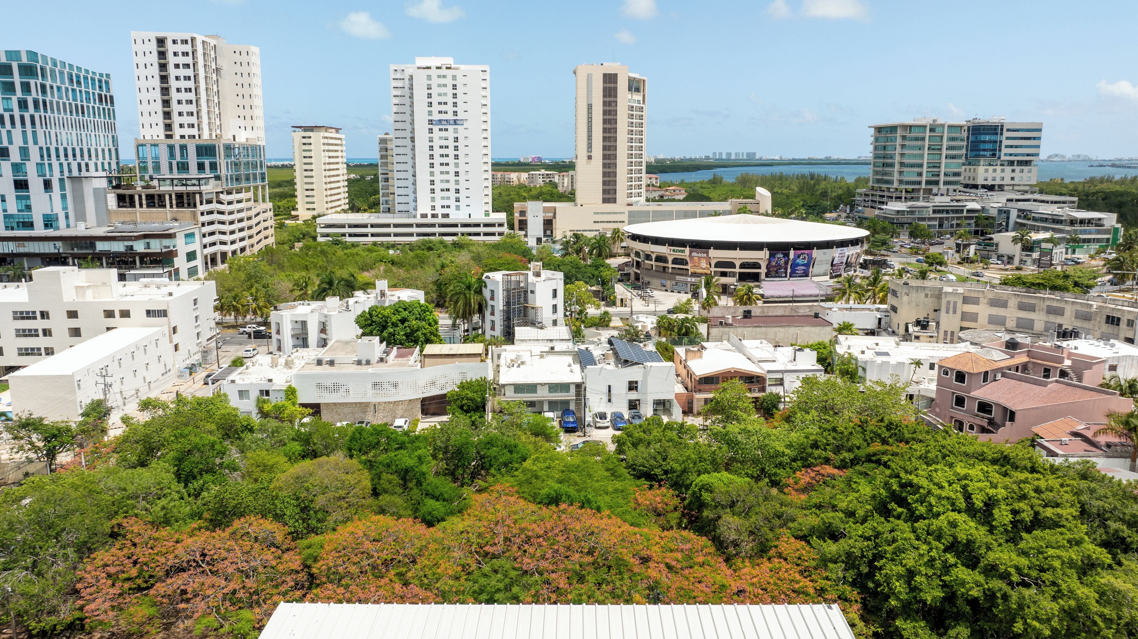 A cityscape with modern high-rise buildings, a stadium, and surrounding greenery.